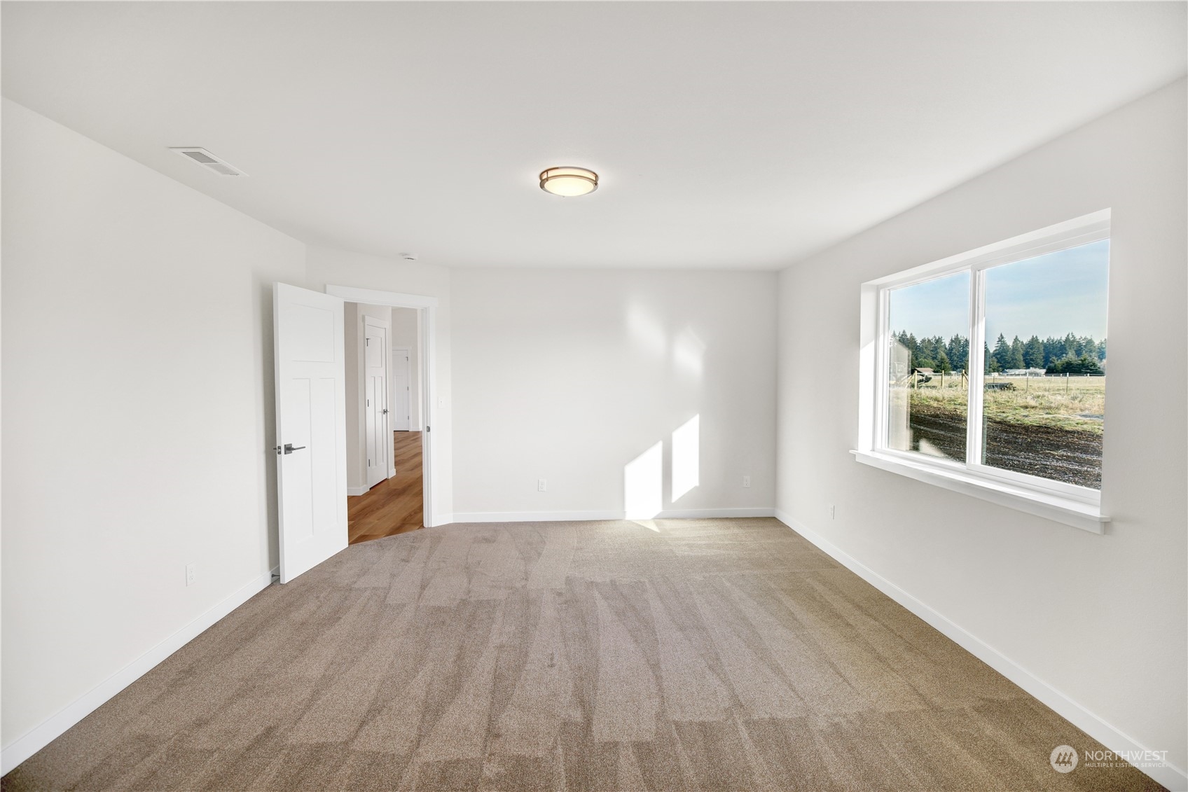 7507 182nd Trail Southwest Rochester, WA 98579 - Photo 6 of 22 a view of an empty room with wooden floor and a window