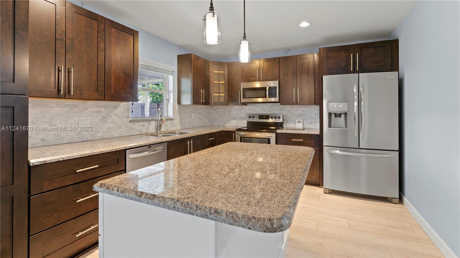 3166 Northwest 68th Court Fort Lauderdale, FL 33309 - Photo 26 of 36 a kitchen with stainless steel appliances granite countertop a refrigerator a sink a stove a microwave and island