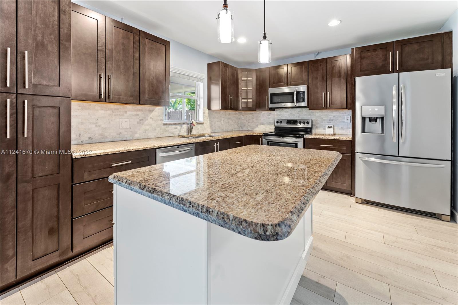 3166 Northwest 68th Court Fort Lauderdale, FL 33309 - Photo 30 of 36 a kitchen with stainless steel appliances granite countertop a refrigerator a sink a stove a microwave and island