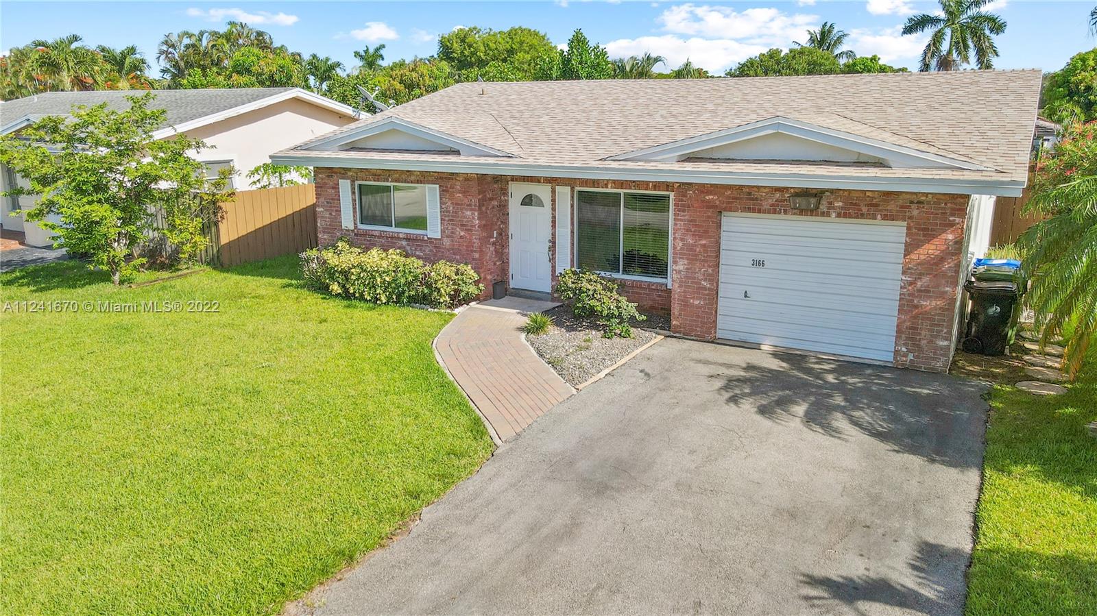 3166 Northwest 68th Court Fort Lauderdale, FL 33309 - Photo 7 of 36 a front view of a house with a garden and yard