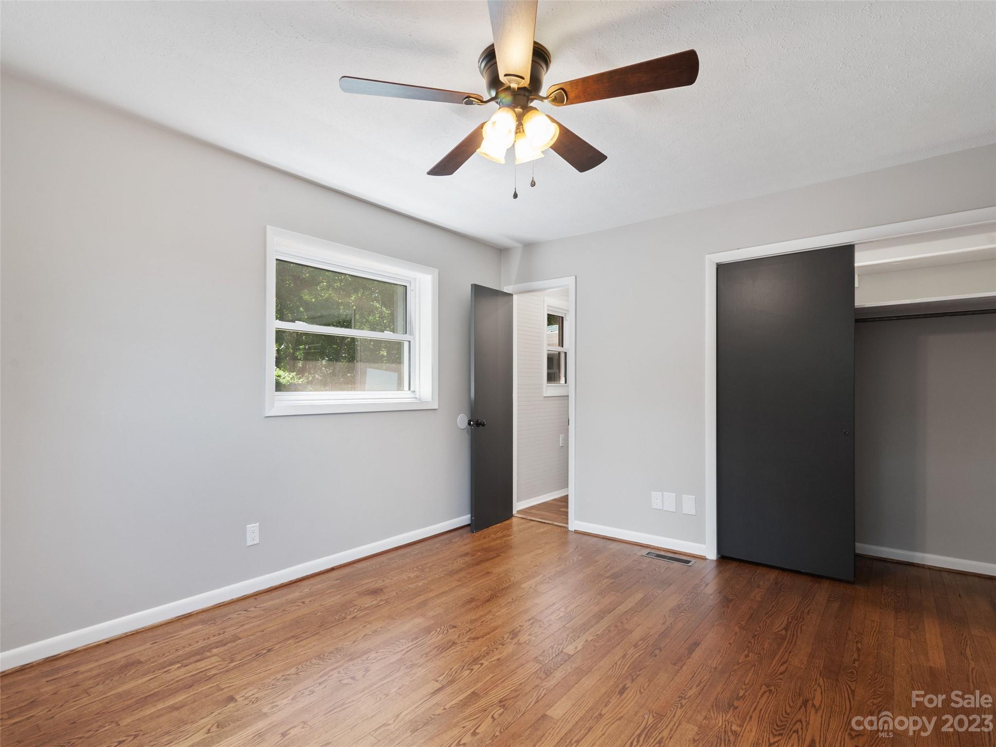 79 Oak Street Clyde, NC 28721 - Photo 13 of 23 an empty room with wooden floor chandelier fan and windows