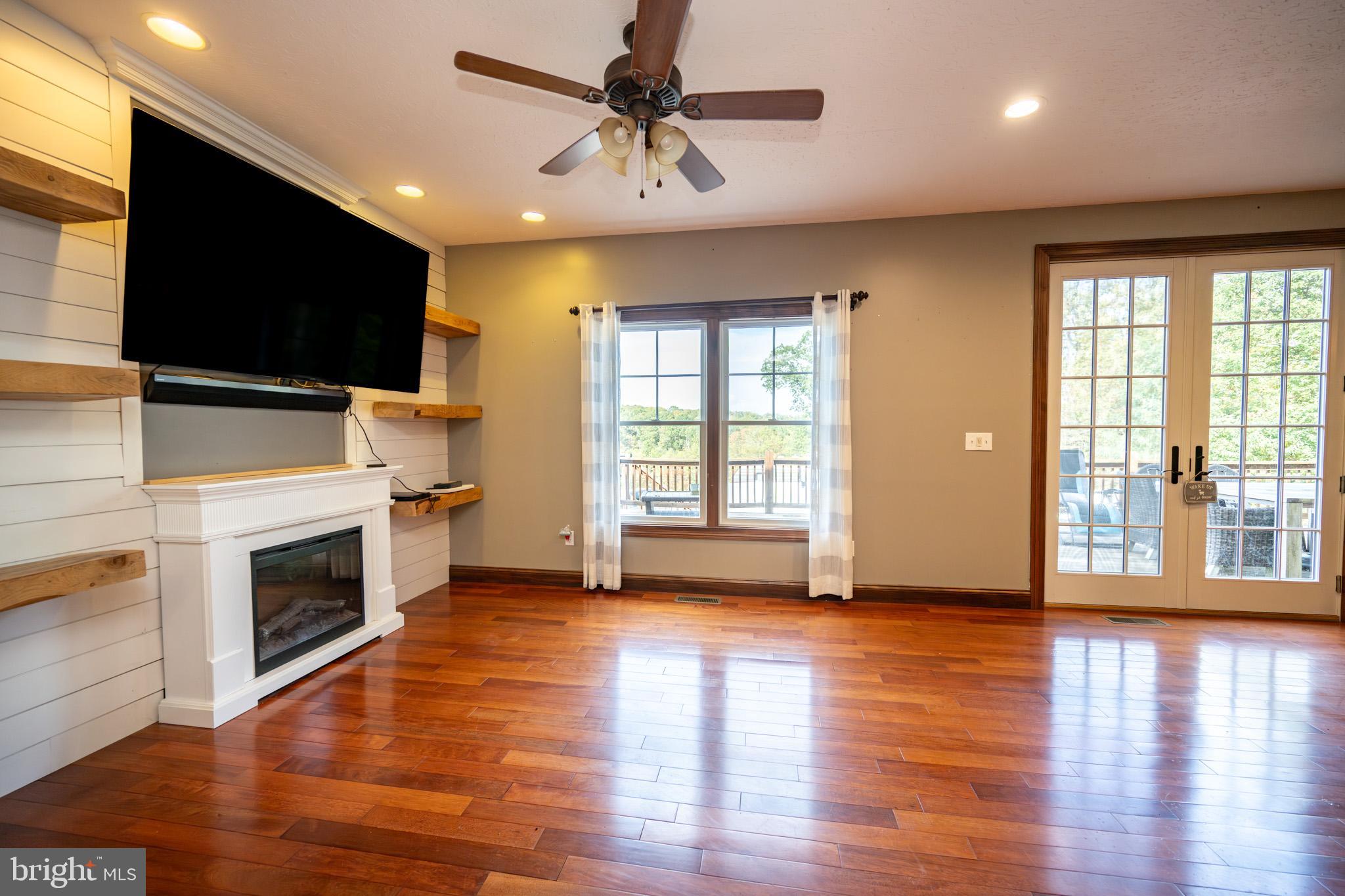 1909 Pysell Crosscut Road Oakland, MD 21550 - Photo 21 of 82 a view of a livingroom with a flat screen tv ceiling fan and hardwood floor