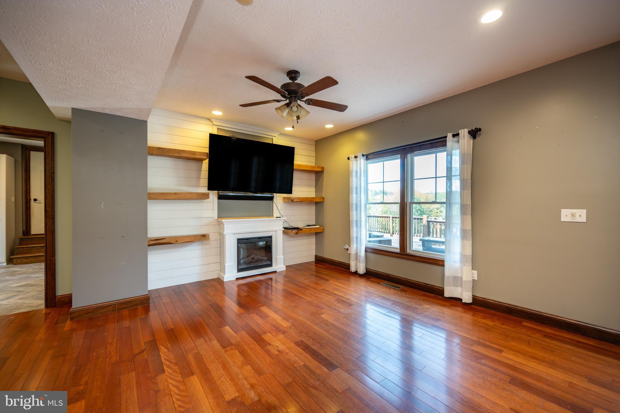 1909 Pysell Crosscut Road Oakland, MD 21550 - Photo 22 of 82 a view of a livingroom with a flat screen tv wooden floor and a ceiling fan