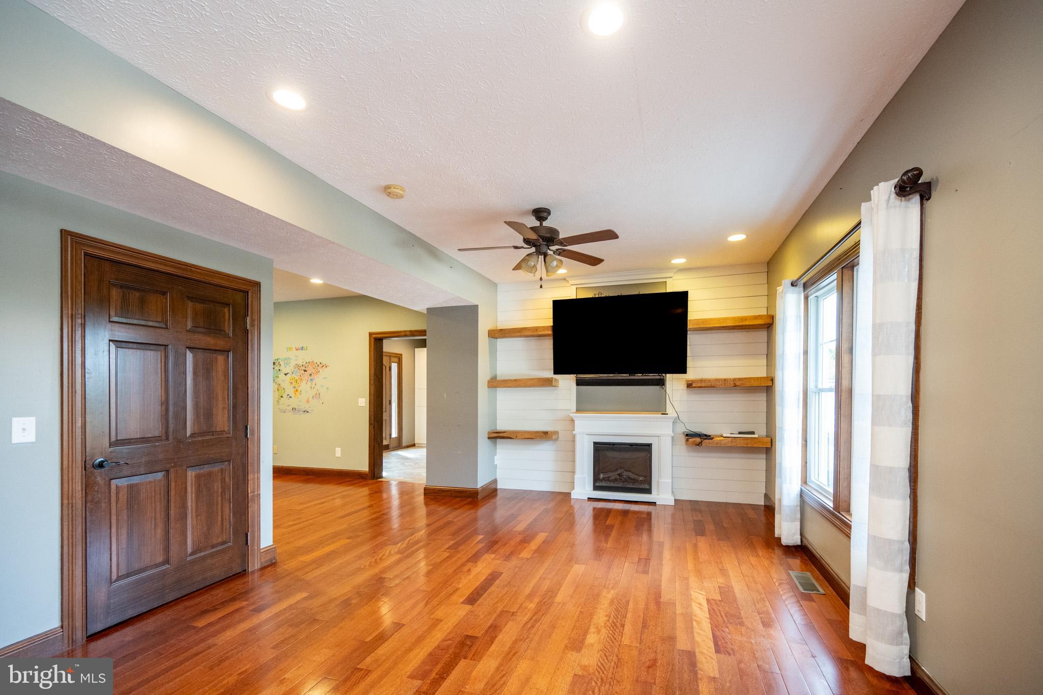 1909 Pysell Crosscut Road Oakland, MD 21550 - Photo 23 of 82 a view of a livingroom with a flat screen tv wooden floor and a ceiling fan