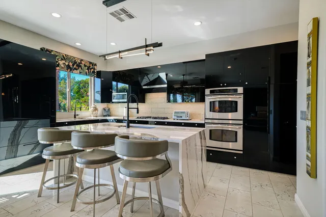 a backyard of a house with table and chairs potted plants and large tree
