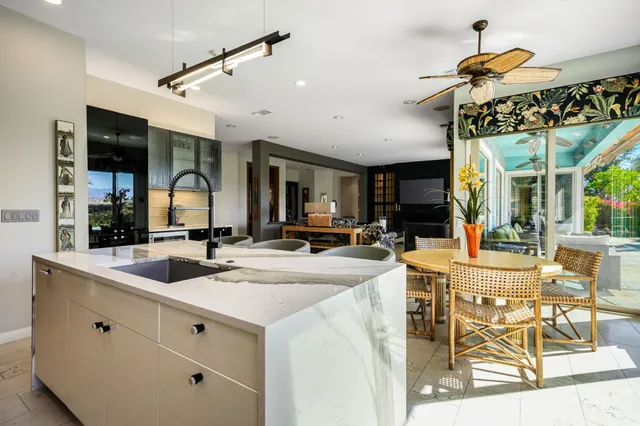 a view of a patio with couches table and chairs potted plants and palm trees
