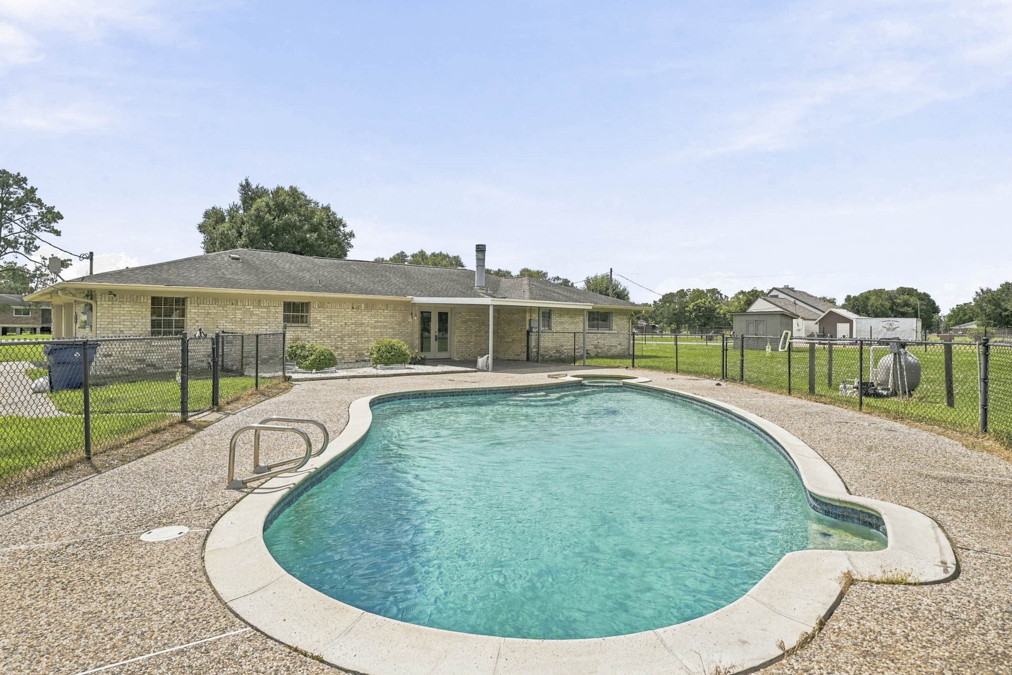 302 Country Road 893 Angleton, TX 77515 - Photo 26 of 26 This property features a spacious backyard with a fenced-in pool, perfect for outdoor relaxation and entertaining. The home has a brick exterior and a covered patio, offering additional outdoor living space.