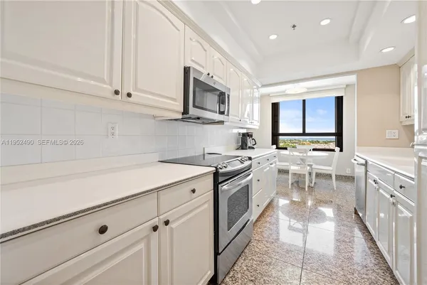 a kitchen with stainless steel appliances granite countertop a stove top oven a sink dishwasher and a refrigerator with wooden cabinets