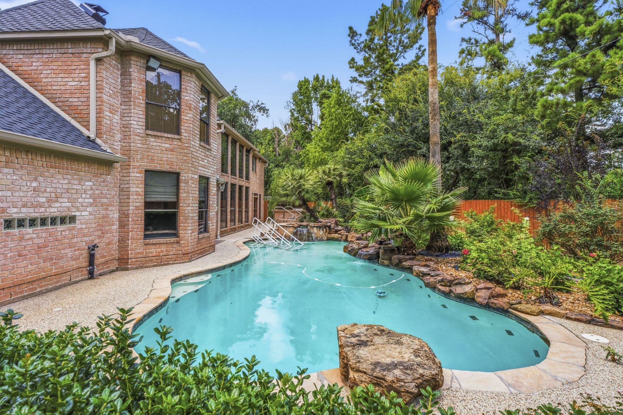 18503 Cabaniss Circle Spring, TX 77379 - Photo 3 of 49 Sneak peak of your own private backyard retreat featuring a resort-style pool and spa with rock waterfalls, lush tropical landscaping, and expansive outdoor living space.