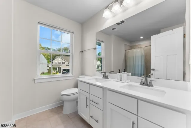 a bathroom with a double vanity sink toilet and a window
