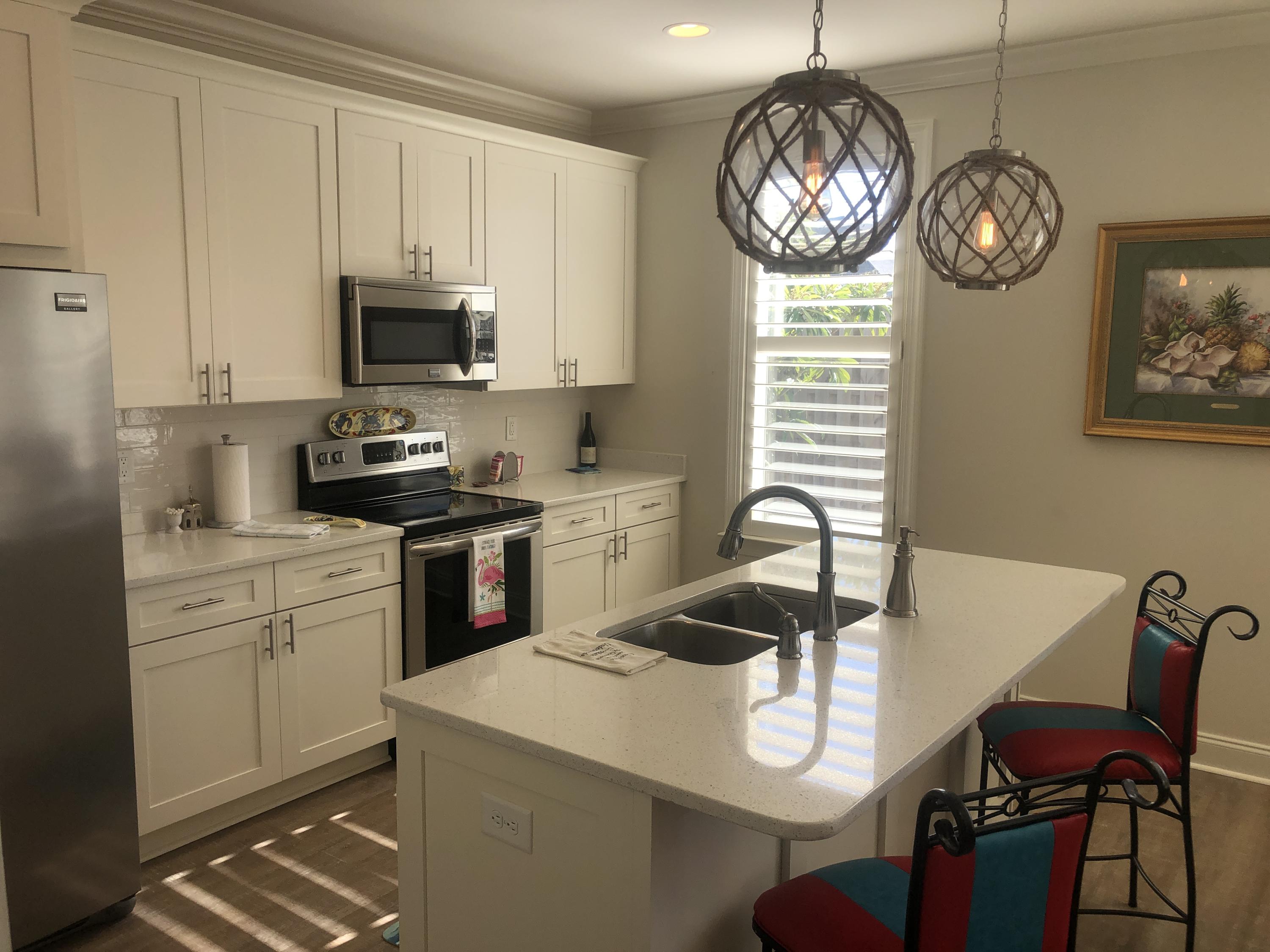 52 Chapman Street Santa Rosa Beach, FL 32459 - Photo 15 of 50 a kitchen with stainless steel appliances a stove a sink a dining table and chairs with wooden floor