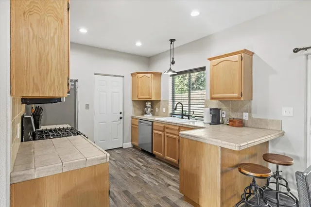a kitchen that has a sink a stove in it and wooden floors
