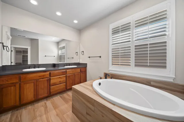 a bathroom with a granite countertop tub sink and mirror