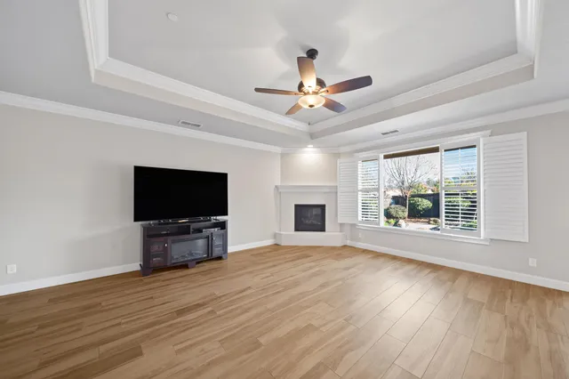 a view of a livingroom with wooden floor a ceiling fan and a window