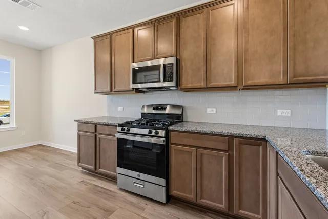 a kitchen with stainless steel appliances granite countertop a stove a microwave and a sink