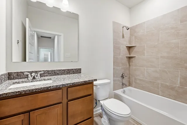 a bathroom with a granite countertop toilet a sink and a bathtub