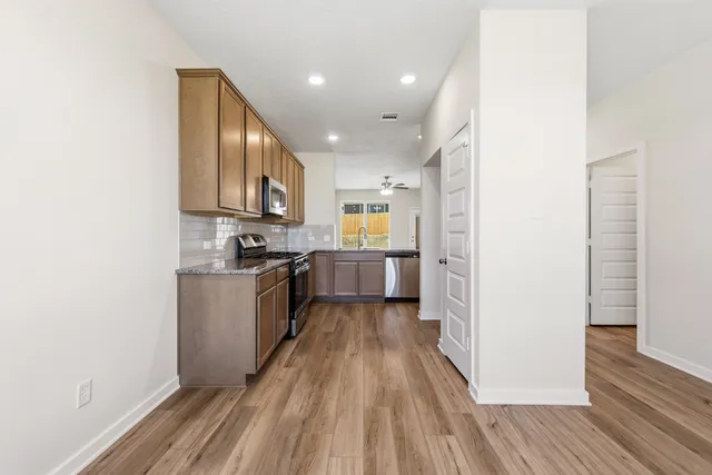 a kitchen with stainless steel appliances granite countertop a refrigerator a stove and a wooden floors