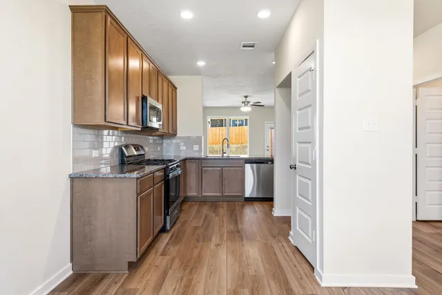 a kitchen with stainless steel appliances granite countertop wooden cabinets a stove top oven a sink and dishwasher