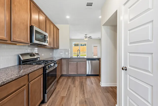 a kitchen with stainless steel appliances granite countertop wooden cabinets a stove top oven a sink and dishwasher