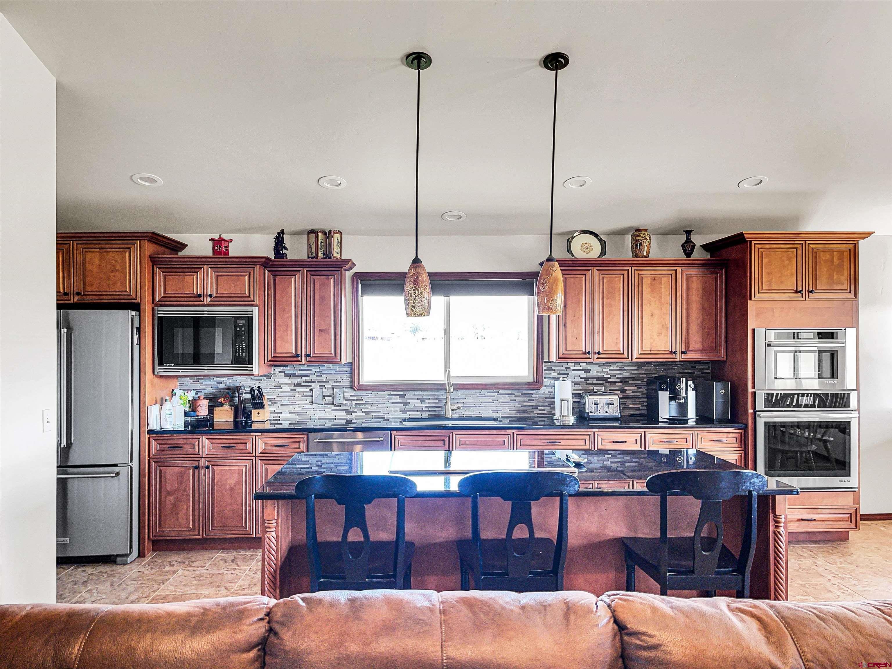 12336 Road 23.25 Loop Cortez, CO 81321 - Photo 16 of 34 a kitchen with granite countertop a stove a sink a dining table and chairs