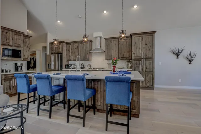 a kitchen with stainless steel appliances granite countertop a sink a stove a dining table and chairs