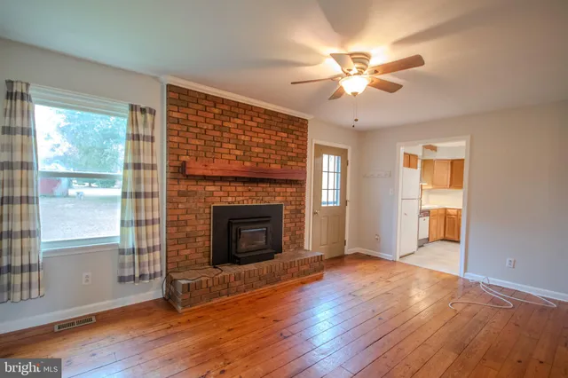 a view of a livingroom with a fireplace wooden floor and windows