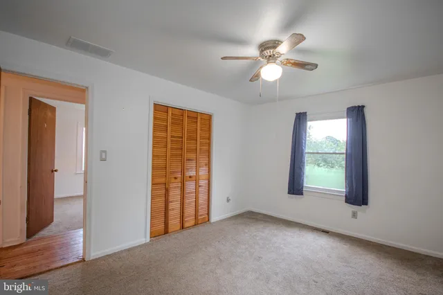 an empty room with windows and fan