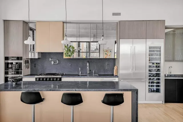 a kitchen with stainless steel appliances granite countertop a sink a stove a refrigerator cabinets and chairs