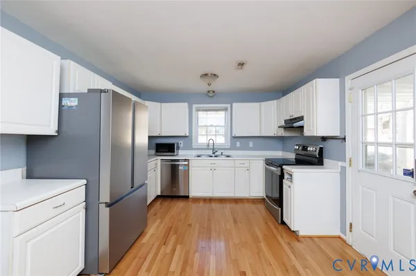 a kitchen with a refrigerator a sink dishwasher a stove and white countertops with wooden floor
