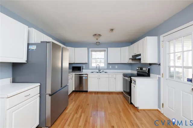 a kitchen with a refrigerator a sink dishwasher a stove and white countertops with wooden floor