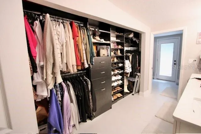 a view of walk in closet with clothes and shoes