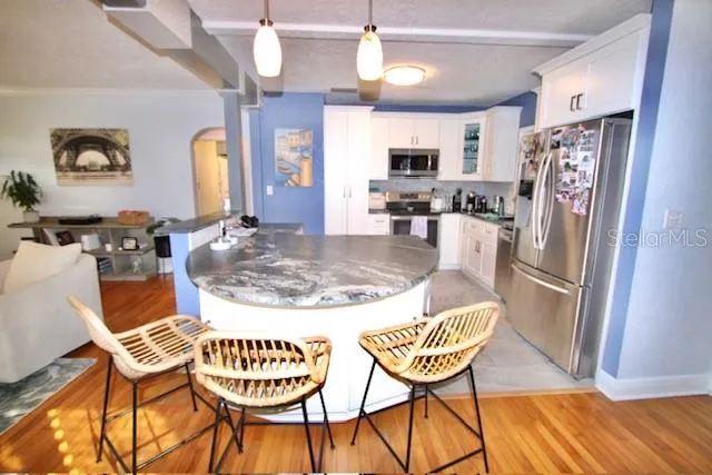a kitchen with stainless steel appliances kitchen island granite countertop a dining table chairs and a refrigerator