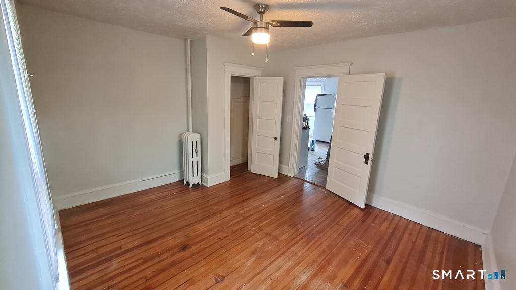 64-66 Ridge Street Manchester, CT 06040 - Photo 5 of 21 an empty room with wooden floor and a ceiling fan