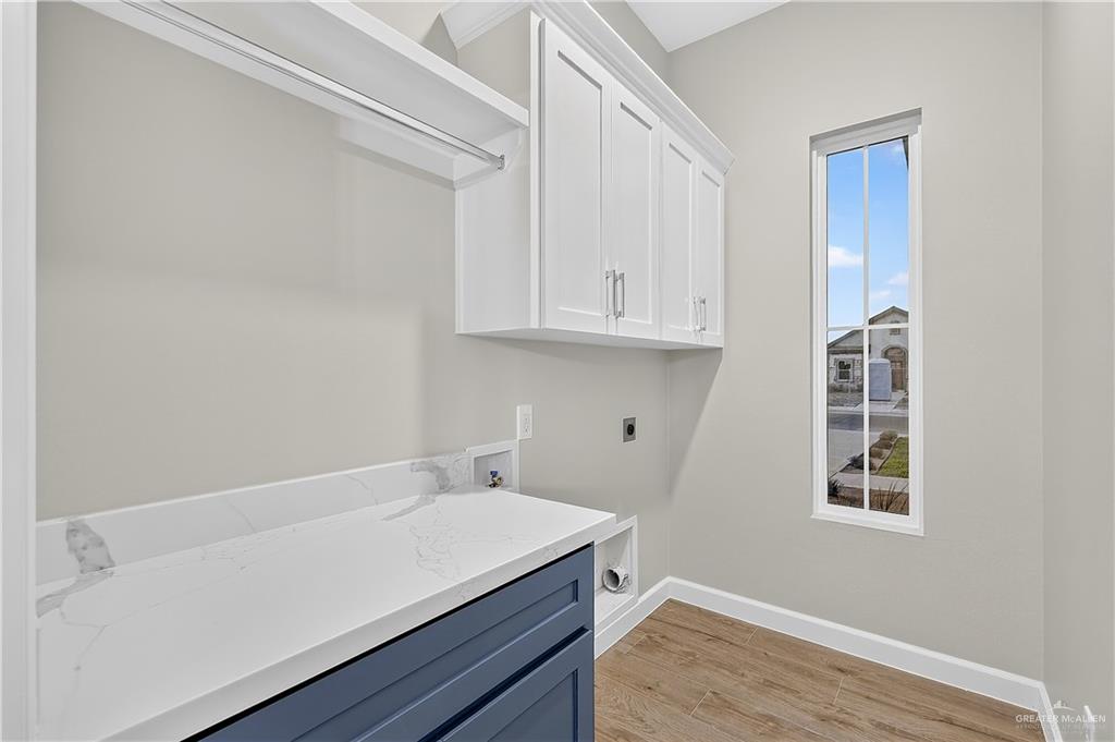 431 Sandy Road Donna, TX 78537 - Photo 19 of 28 White upper cabinetry, white shelving with hanging rod, a white countertop with a backsplash, a navy-colored lower cabinet, and wood-finish flooring