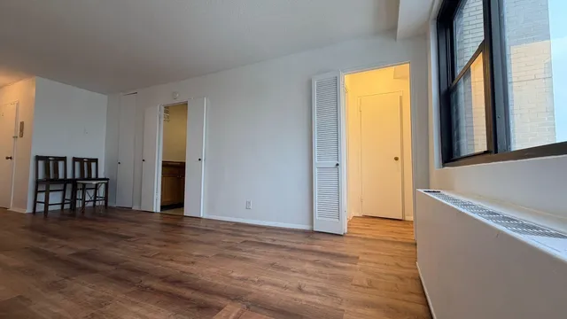 a view of empty room with wooden floor and fan