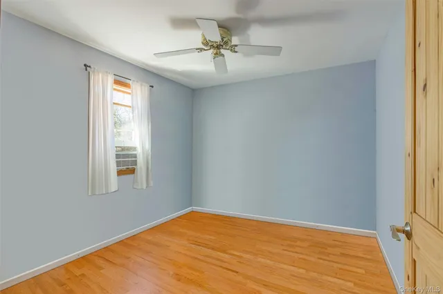 an empty room with a window and a ceiling fan