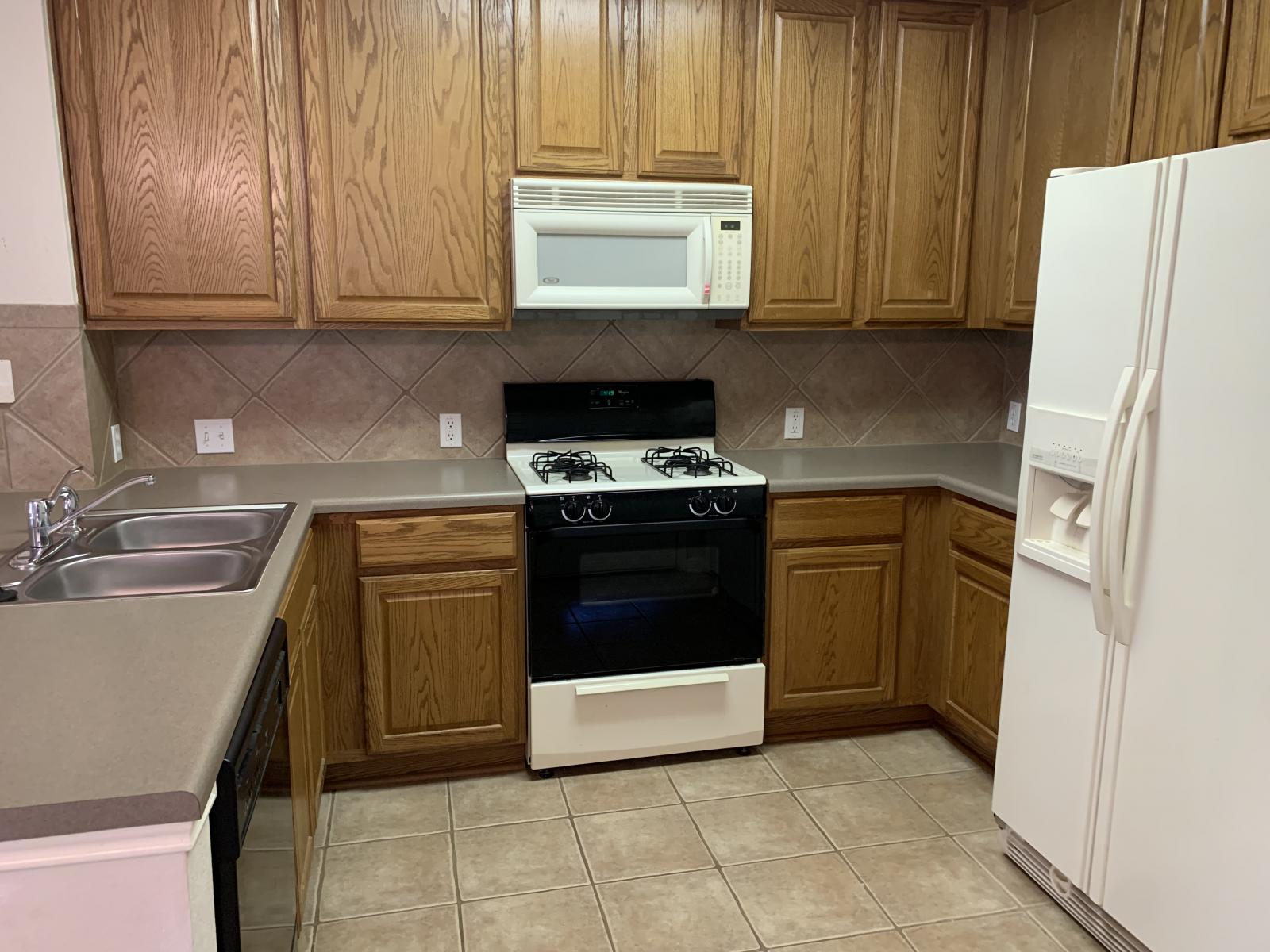 11000 Anderson Mill Road, Unit 29 Austin, TX 78750 - Photo 26 of 27 a kitchen with a stove top oven cabinets and a refrigerator