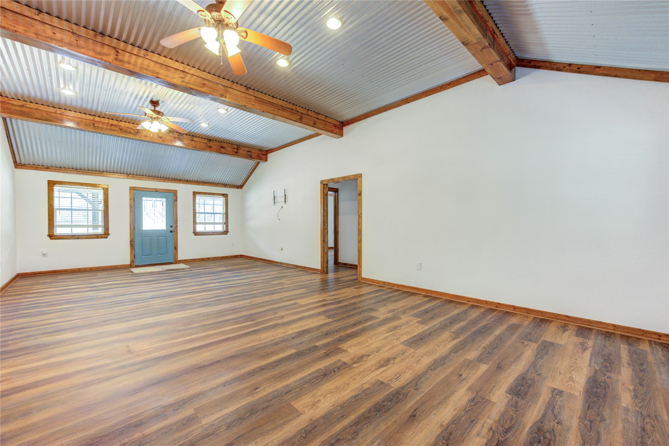 8805 Sun Oil Road Brenham, TX 77833 - Photo 15 of 50 Spacious living area with rustic charm, featuring vaulted ceilings with exposed beams, wood accents, and warm wood flooring, creating a cozy and inviting atmosphere.