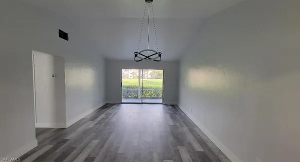 a view of a room with wooden floor a ceiling fan and windows