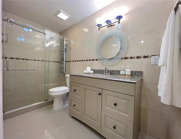 a bathroom with a granite countertop sink mirror toilet and shower