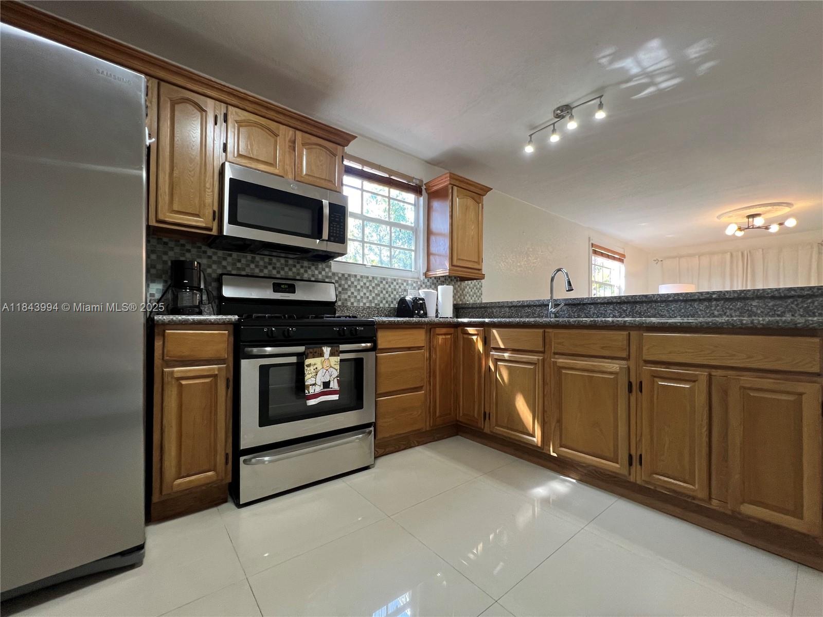 636 Northwest 11th Street, Unit 636 Miami, FL 33136 - Photo 4 of 17 a kitchen with stainless steel appliances granite countertop a stove top oven microwave and cabinets