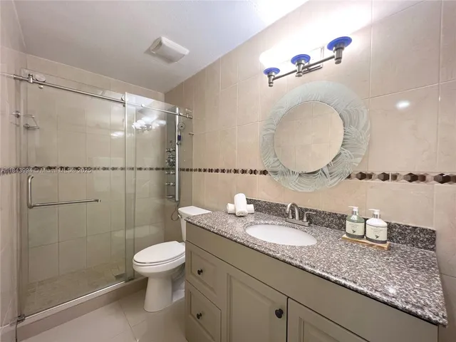 a bathroom with a granite countertop sink a toilet and a mirror
