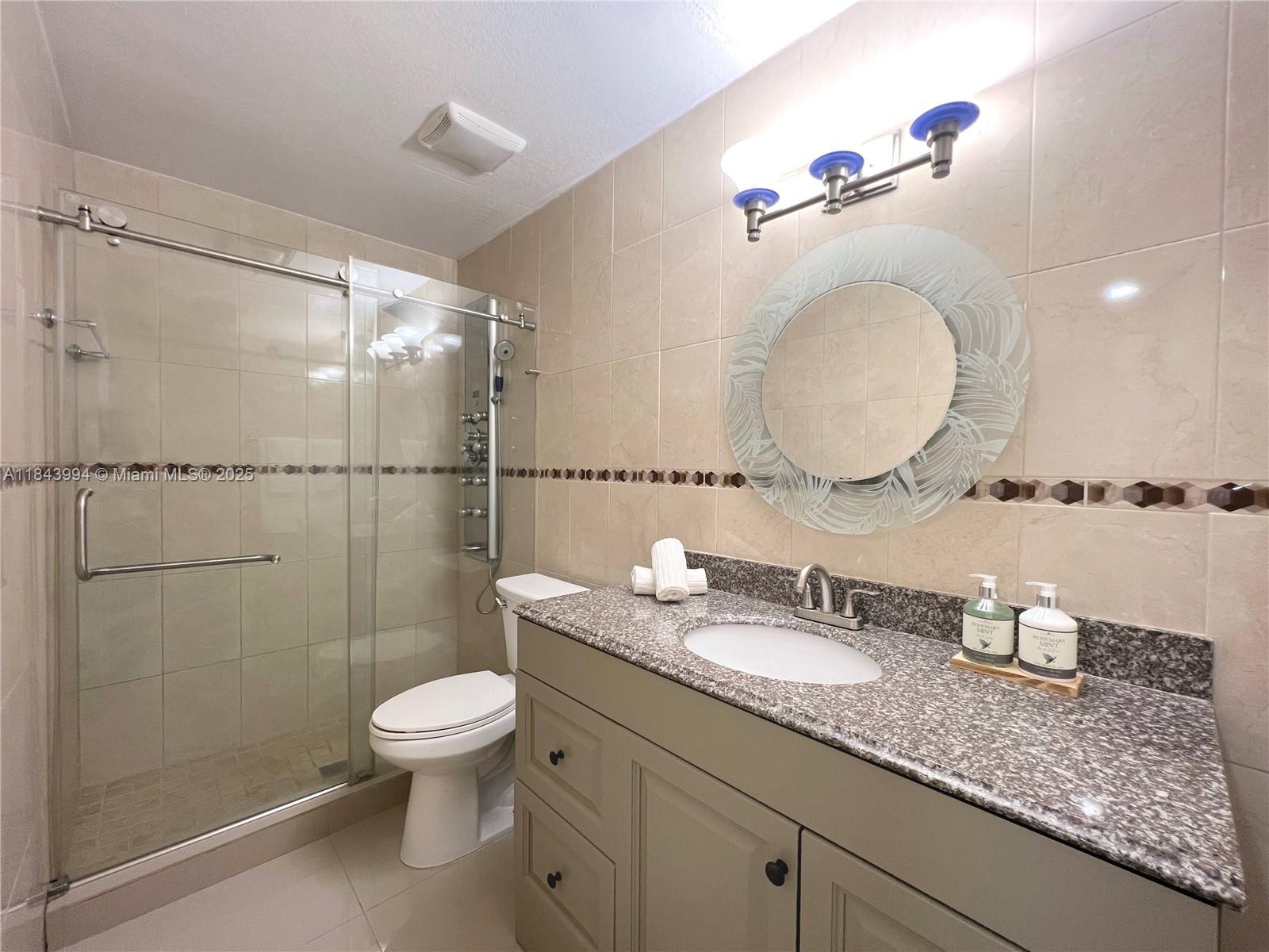 636 Northwest 11th Street, Unit 636 Miami, FL 33136 - Photo 10 of 17 a bathroom with a granite countertop sink a toilet and a mirror