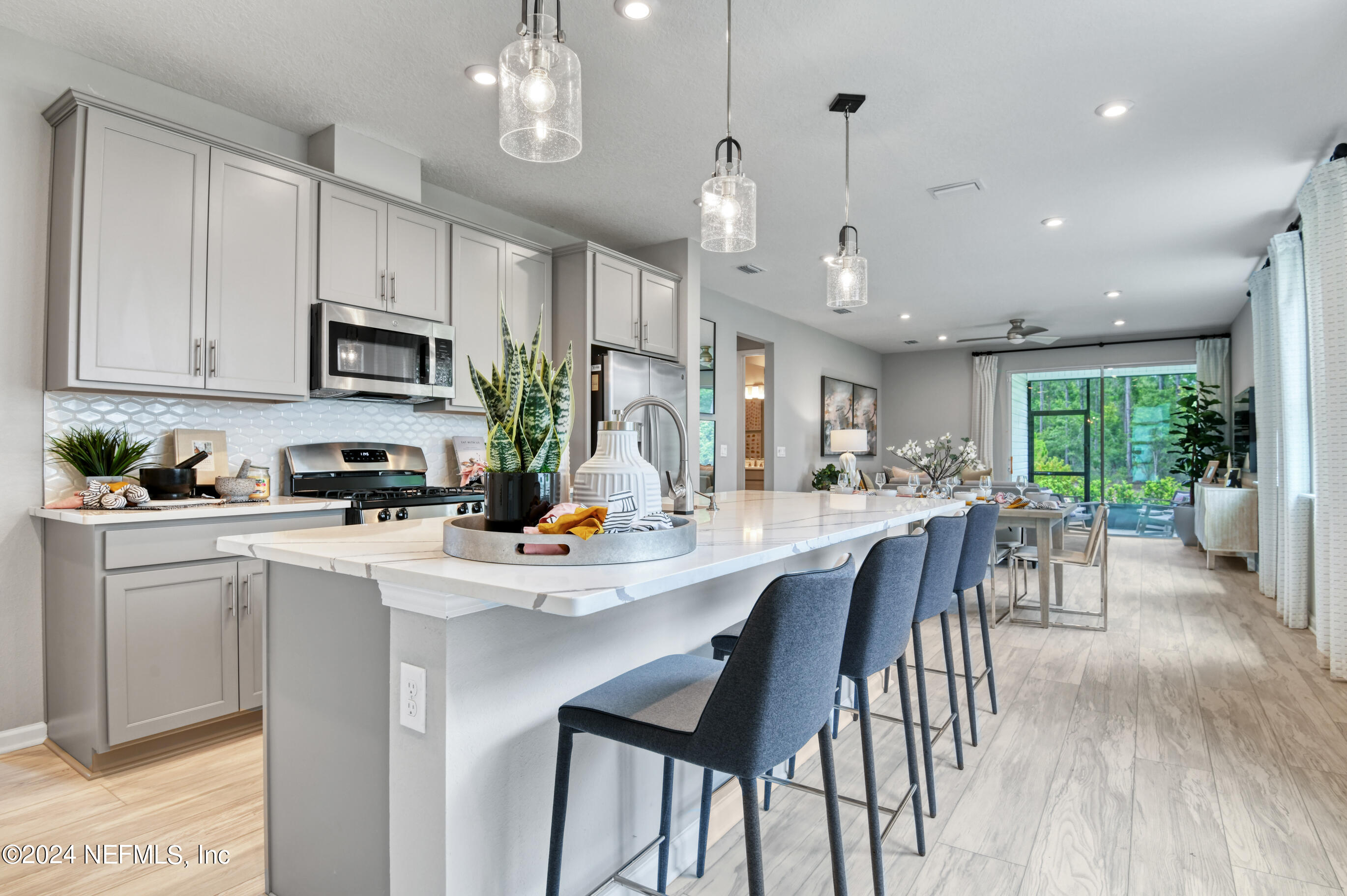 7213 Red Timber Road Jacksonville, FL 32244 - Photo 6 of 17 a kitchen with stainless steel appliances kitchen island granite countertop a stove a refrigerator a sink a dining table and chairs with wooden floor
