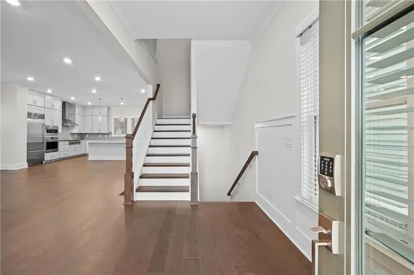 a view of a hallway with stairs to livingroom with wooden floor