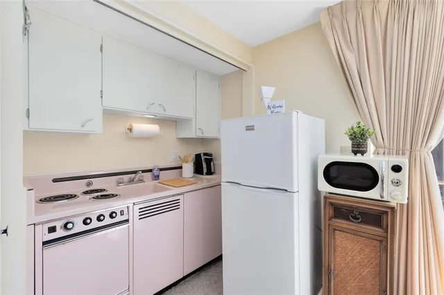 a kitchen with a refrigerator a stove and white cabinets