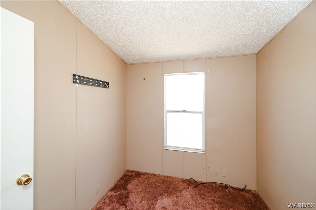 16435 South Wyatt Earp Road Yucca, AZ 86438 - Photo 14 of 57 Room featuring a single-pane window, textured ceiling, and a wall-mounted bracket