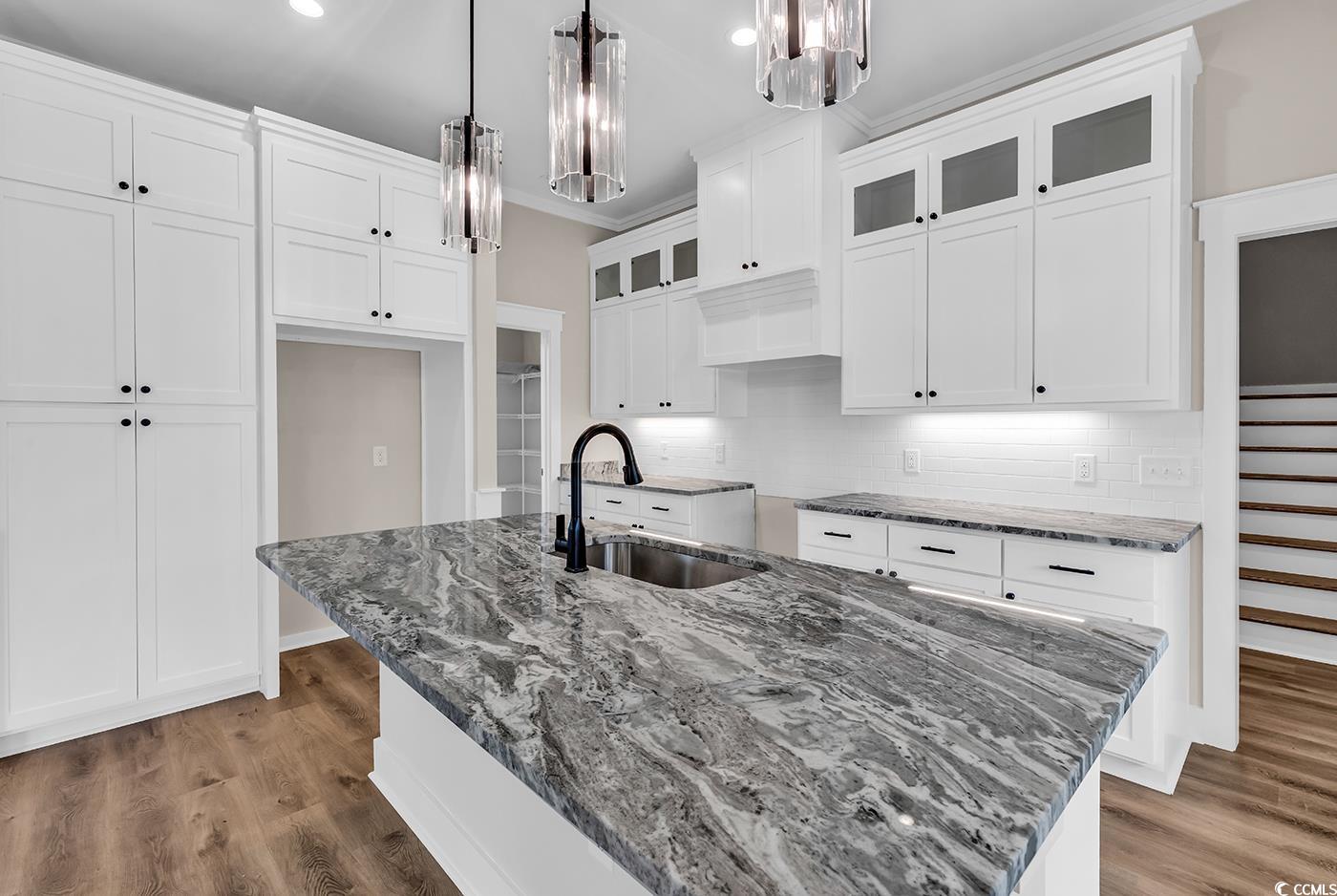 713 Horry Road Aynor, SC 29511 - Photo 12 of 40 Kitchen featuring tasteful backsplash, dark stone counters, glass insert cabinets, white cabinetry, and a center island with sink