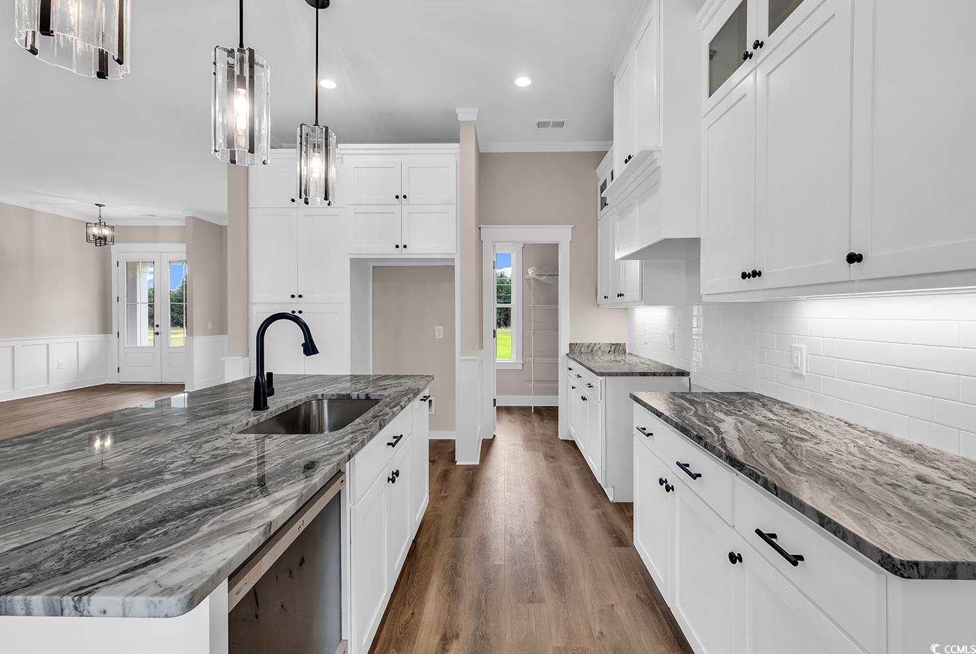 713 Horry Road Aynor, SC 29511 - Photo 13 of 40 Kitchen featuring dark stone counters, white cabinetry, dark wood-style floors, ornamental molding, and a center island with sink