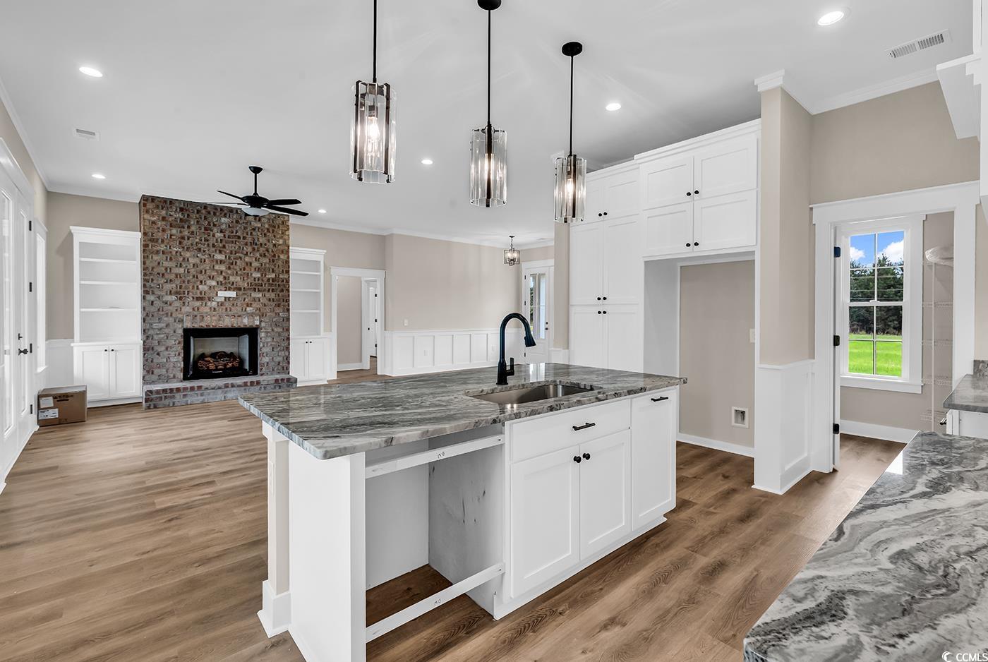 713 Horry Road Aynor, SC 29511 - Photo 14 of 40 Kitchen featuring dark stone countertops, white cabinets, light wood-type flooring, a fireplace, and ornamental molding